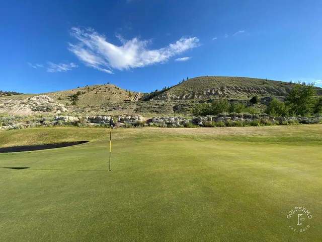 A golfer standing over a shot at Old Works, with the mountains in the distance.