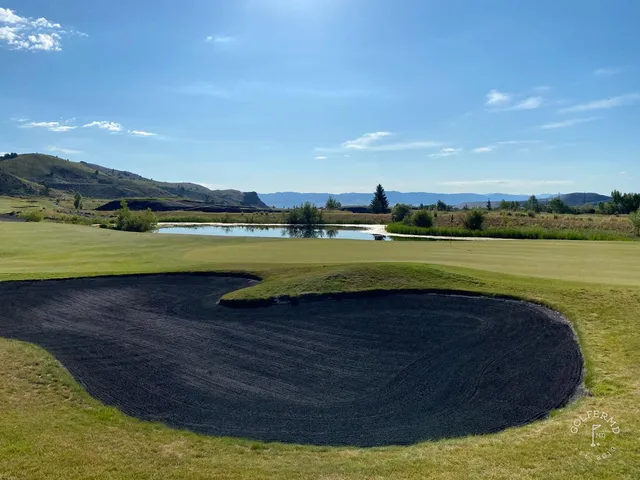 A golfer hitting from the fairway at Old Works, with black sand along the hole.