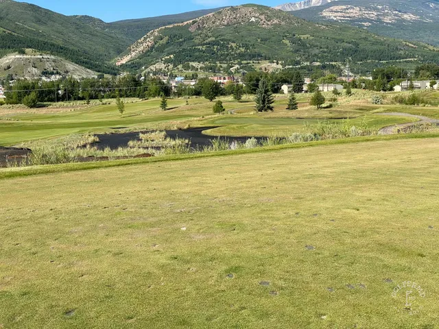 Golfers on a green at Old Works, with the mountains on the horizon.