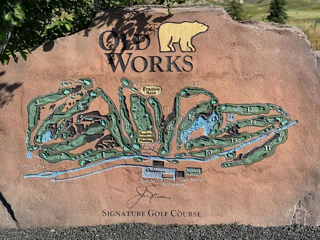 A wide fairway at Old Works dropping toward a green, with black sand along the edges.