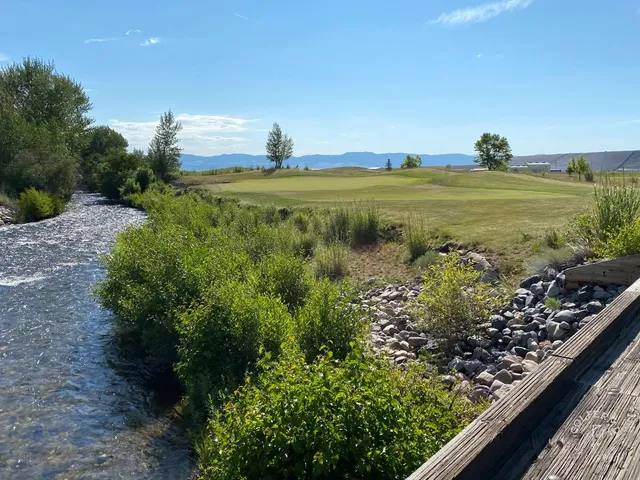 A fairway at Old Works running between black waste areas toward the mountains.