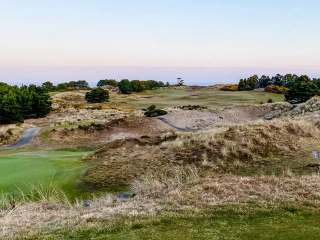 A fairway at Pacific Dunes lined with beach grass, running toward the water.