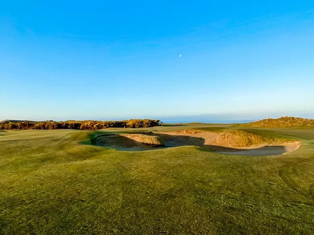 Golfers on a tee at Pacific Dunes, with the Pacific behind them.