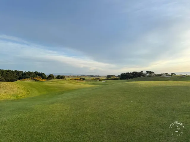 A green and flagstick at Pacific Dunes, seen from a rise, with the ocean behind the hole.