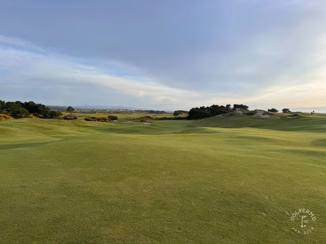 A close view of a flagstick at Pacific Dunes, with the Pacific behind the green.