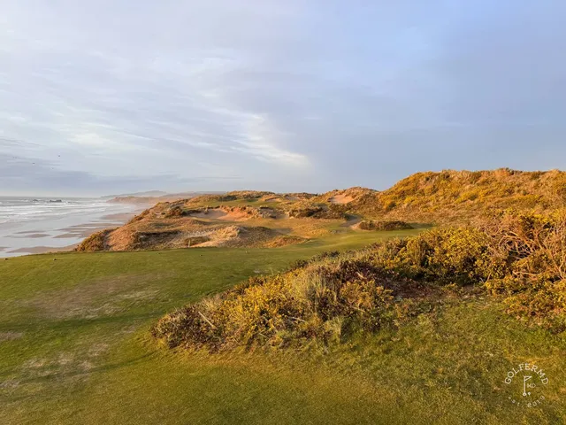 A green and flagstick at Pacific Dunes, with a bunker in front and the water beyond.