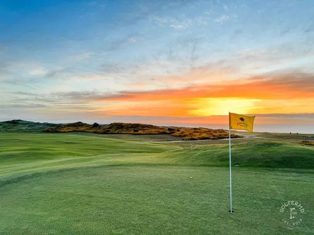 A green and flagstick at Pacific Dunes, with sand in front and the gorse around the hole.