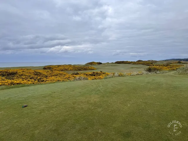 A green and flagstick at Pacific Dunes, seen from the tee, with the ocean behind the hole.