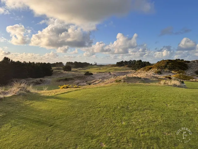 A golfer hitting a shot from the fairway at Pacific Dunes, with the ocean ahead.
