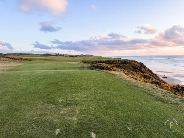 A group of golfers at Pacific Dunes, with the course and the ocean behind them.