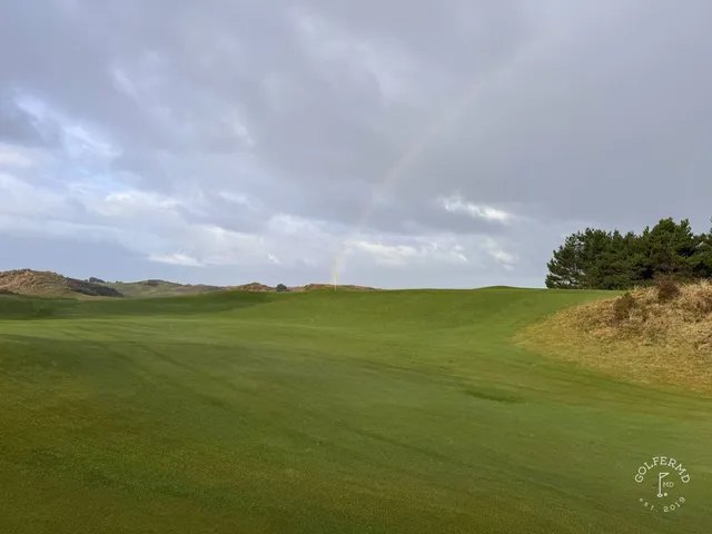 A close view of a flagstick at Pacific Dunes, with the dunes and the Pacific beyond.
