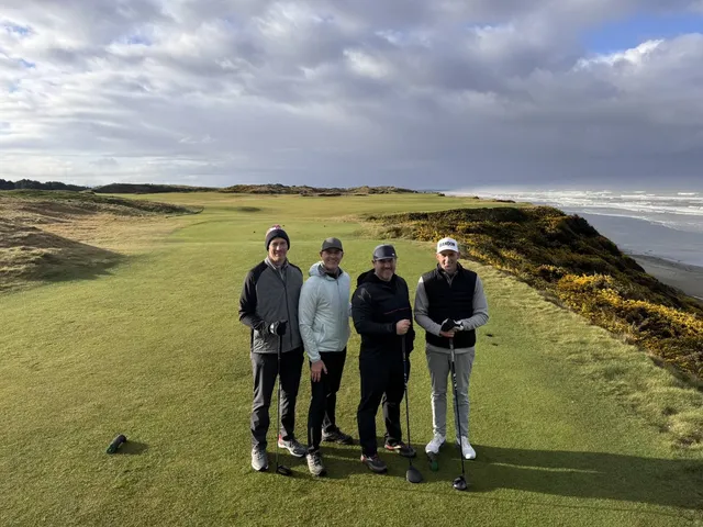 A green and flagstick at Pacific Dunes, with sand short of the green and the water beyond.