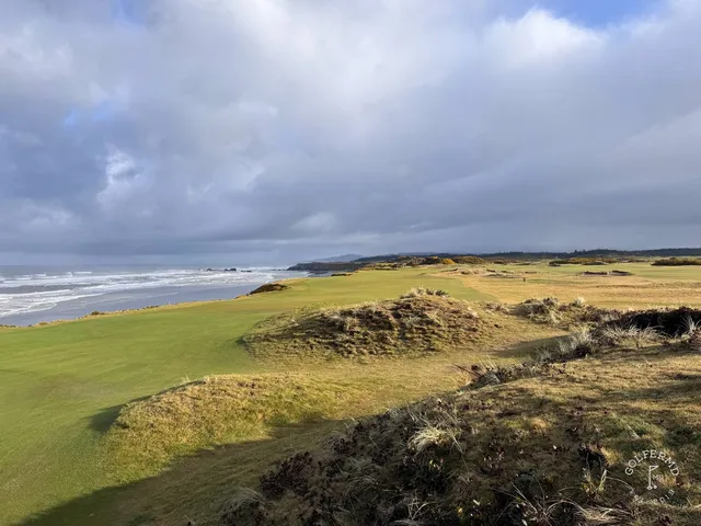A close view of a flagstick at Pacific Dunes, with the Pacific filling the background.