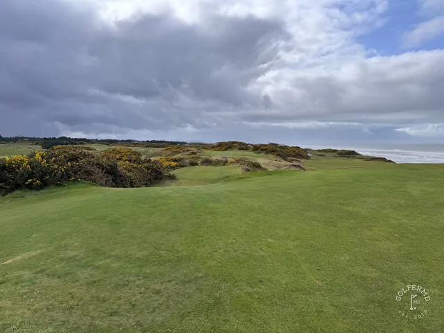 A green and flagstick at Pacific Dunes, with a bunker in front and the Pacific behind the hole.