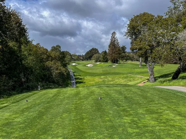 A green and flagstick at Pasatiempo Golf Club, with bunkers in front and trees around the hole.