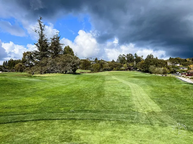 A wide fairway at Pasatiempo Golf Club, with trees along the right and hills beyond.