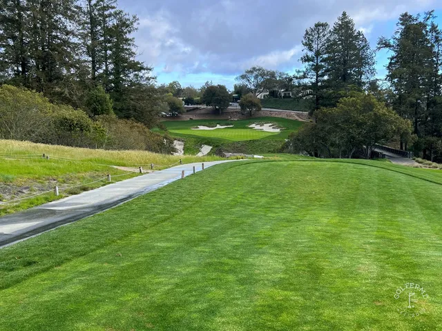 A wide fairway at Pasatiempo Golf Club, with trees and a hillside of houses in the distance.
