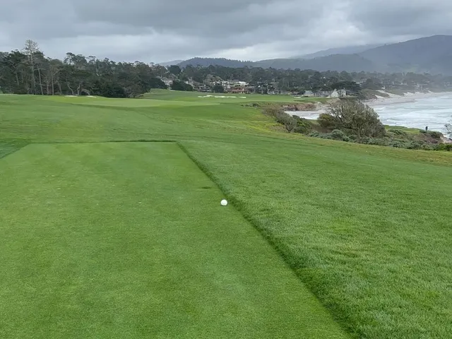 A fairway running toward the ocean at Pebble Beach Golf Links, with cypress trees along both sides.