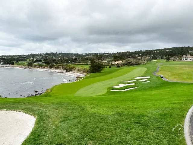 A wide fairway leading to a green at Pebble Beach Golf Links, with cypress trees and the ocean in the distance.
