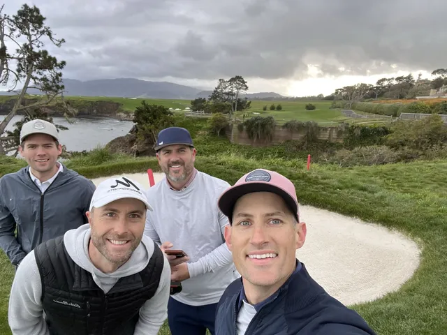 Three men posing for a photo on the coast at Pebble Beach Golf Links, with the ocean and cypress trees behind them.