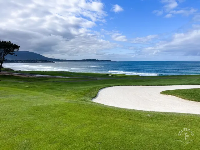 Two people walking a path beside the ocean at Pebble Beach Golf Links.