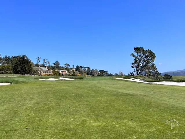 A fairway running toward the ocean at Pebble Beach Golf Links, lined with cypress trees.