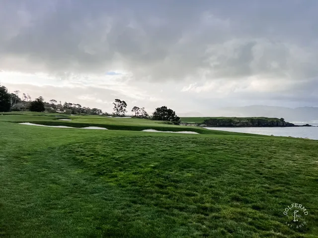 Two people walking a fairway at Pebble Beach Golf Links, with cypress trees and the ocean beside them.