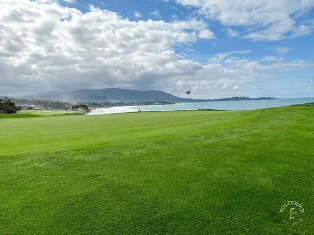A golfer on a tee at Pebble Beach Golf Links, with another person standing beside them and the ocean beyond.
