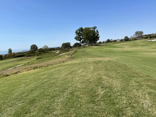 A green and flagstick on the bluffs above the ocean at Pelican Hill Ocean North Course.