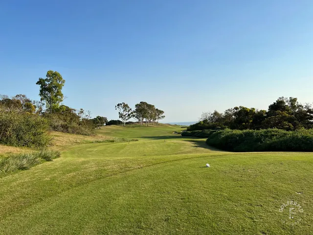 A green and flagstick beside a bunker at Pelican Hill Ocean North Course, with the ocean on the horizon.