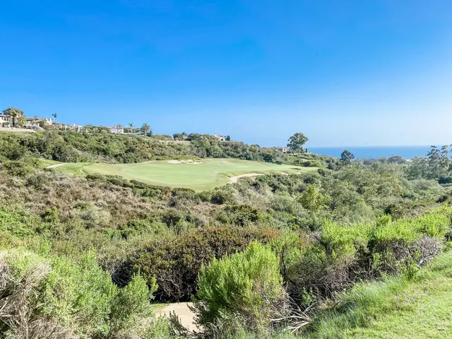 A green and flagstick on the bluff at Pelican Hill Ocean South Course, with the ocean and coastline beyond.