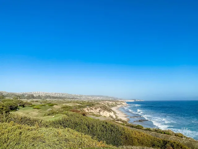 A green and flagstick on the bluff at Pelican Hill Ocean South Course, with the ocean beyond.