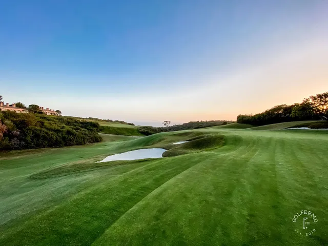 A green and flagstick above the ocean at Pelican Hill Ocean South Course, with a bunker short of the green.