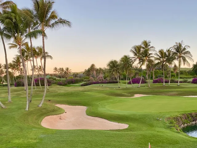 A fairway at Poipu Bay Golf Course running toward the ocean, with palm trees along the right side.