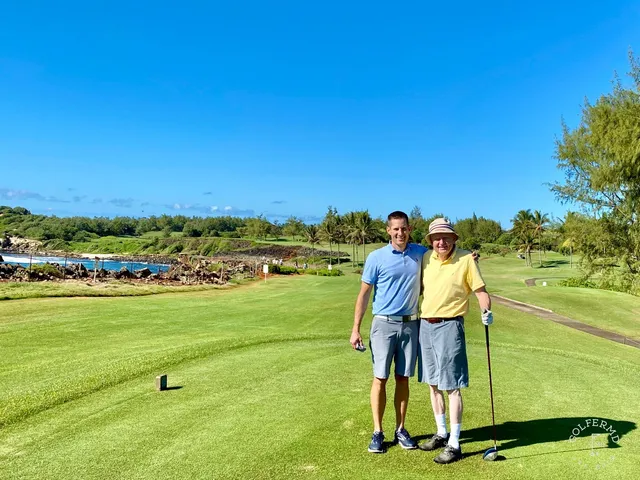 A fairway at Poipu Bay lined with palm trees, running toward the water.
