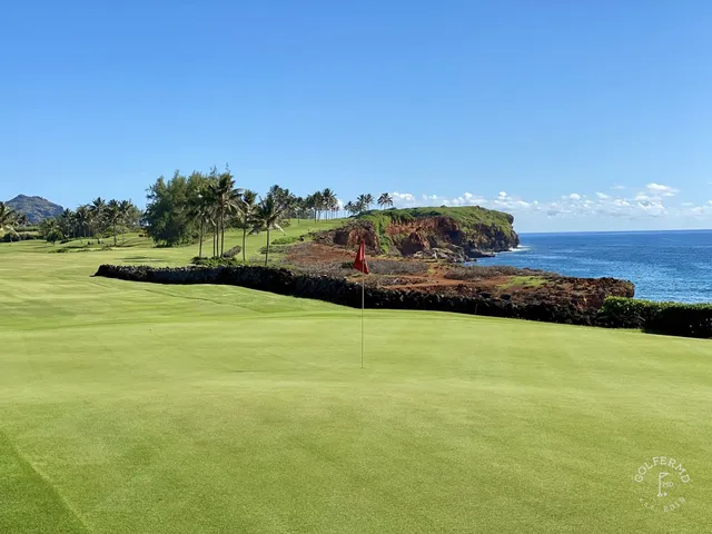 A close view of a green and flagstick at Poipu Bay, with the ocean behind the hole.