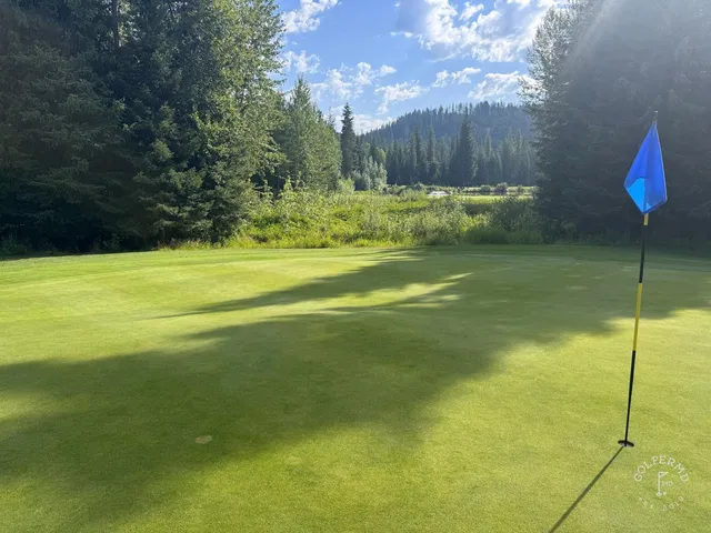 A wide fairway at Priest Lake, with mountains and the water in the distance.