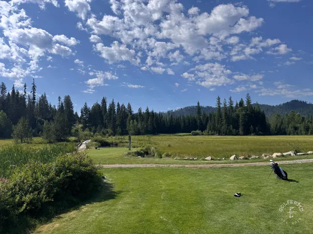 A wide hole at Priest Lake, with pine forest and the lake on the horizon.