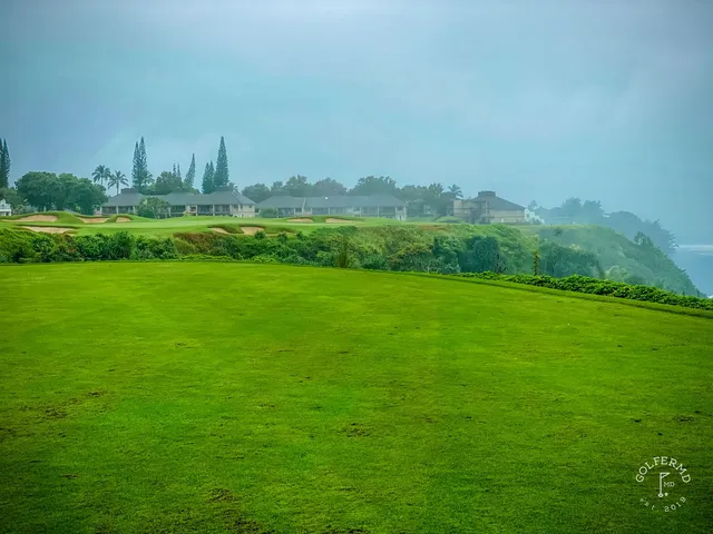 A fairway and green at Princeville Makai, with sand bunkers and the Pacific on the horizon.