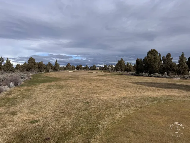 A fairway at Pronghorn running through the high desert, with the red hills beyond.