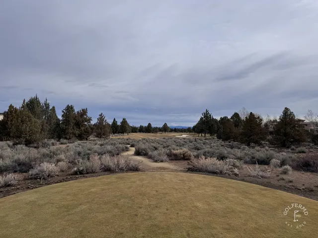 A green and flagstick at Pronghorn, with a bunker in front and the hills behind the hole.
