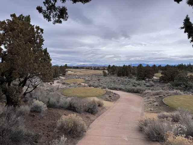 A green and flagstick at Pronghorn, seen from the fairway, with a bunker short of the green.