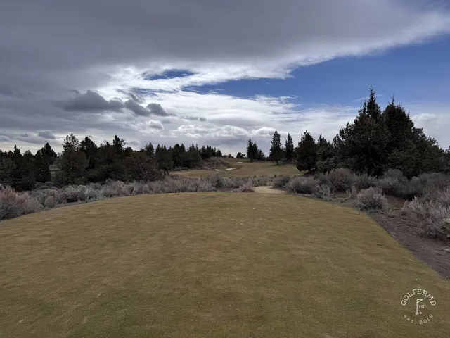 A golfer putting on a green at Pronghorn, with the hills beyond the hole.