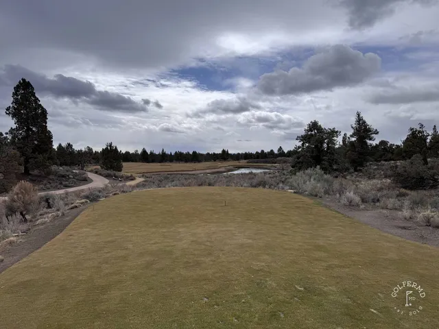 A close view of a green and flagstick at Pronghorn, with the mountains behind it.
