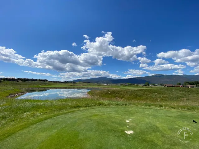 A golfer putting on a green at The Ranch Club, with the mountains beyond the hole.