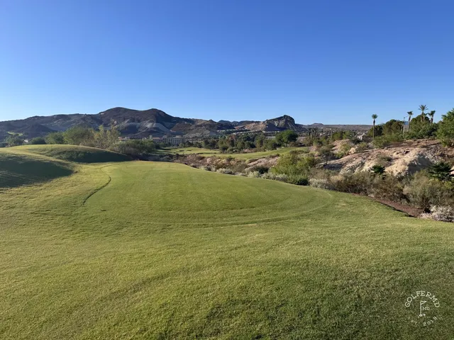 A green and flagstick at Reflection Bay, with a bunker in front and the lake behind the hole.
