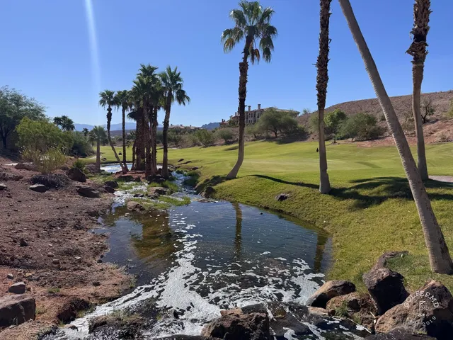 A close view of a green and flagstick at Reflection Bay, with the water behind the hole.