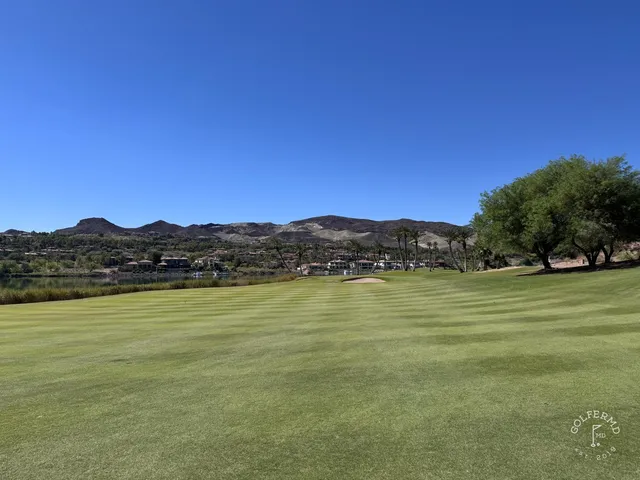 A green and flagstick at Reflection Bay, seen from a rise, with Lake Mead beyond.