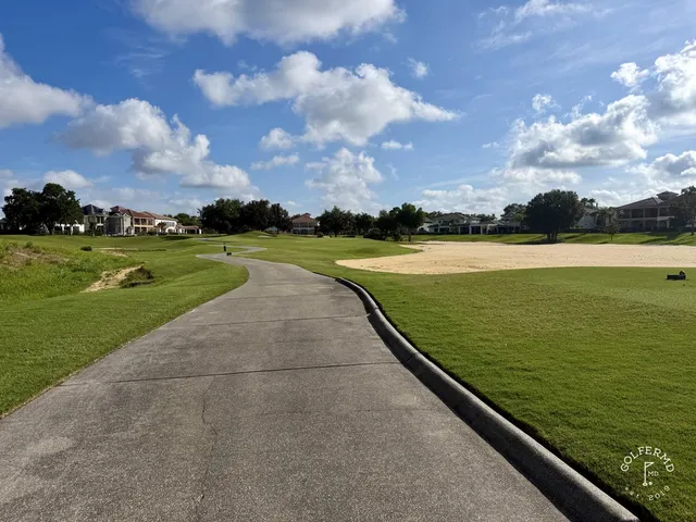 A green and flagstick at Reunion Resort's Watson Course, with a pond along the right side and a sand bunker in the foreground.