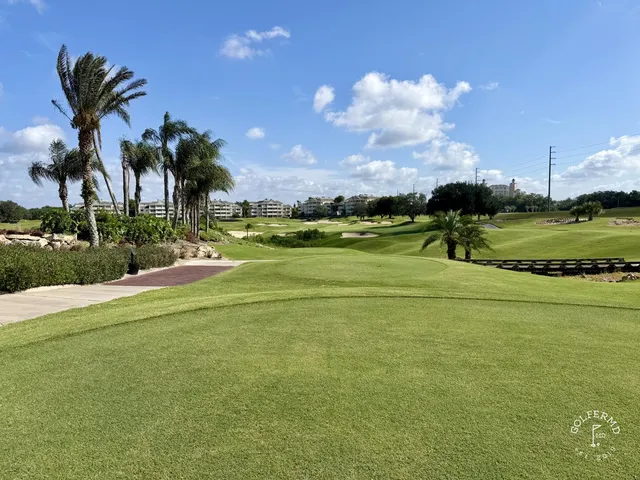 A green and flagstick at the Watson Course, with a sand bunker in front and a pond behind the green.